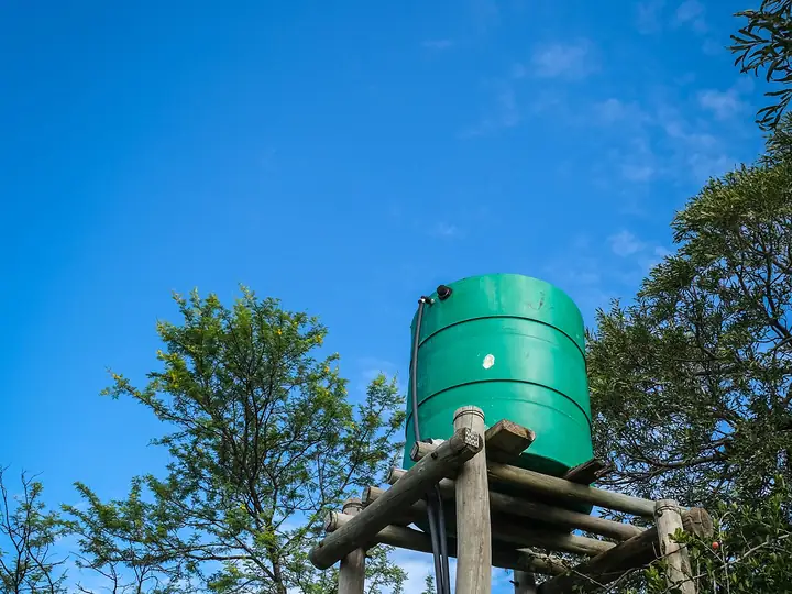 Green water storage tank raised on a wooden stand